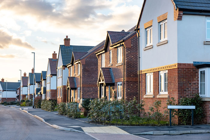 row of modern suburban houses with gardens and a street in the foreground, showcasing residential architecture and community living